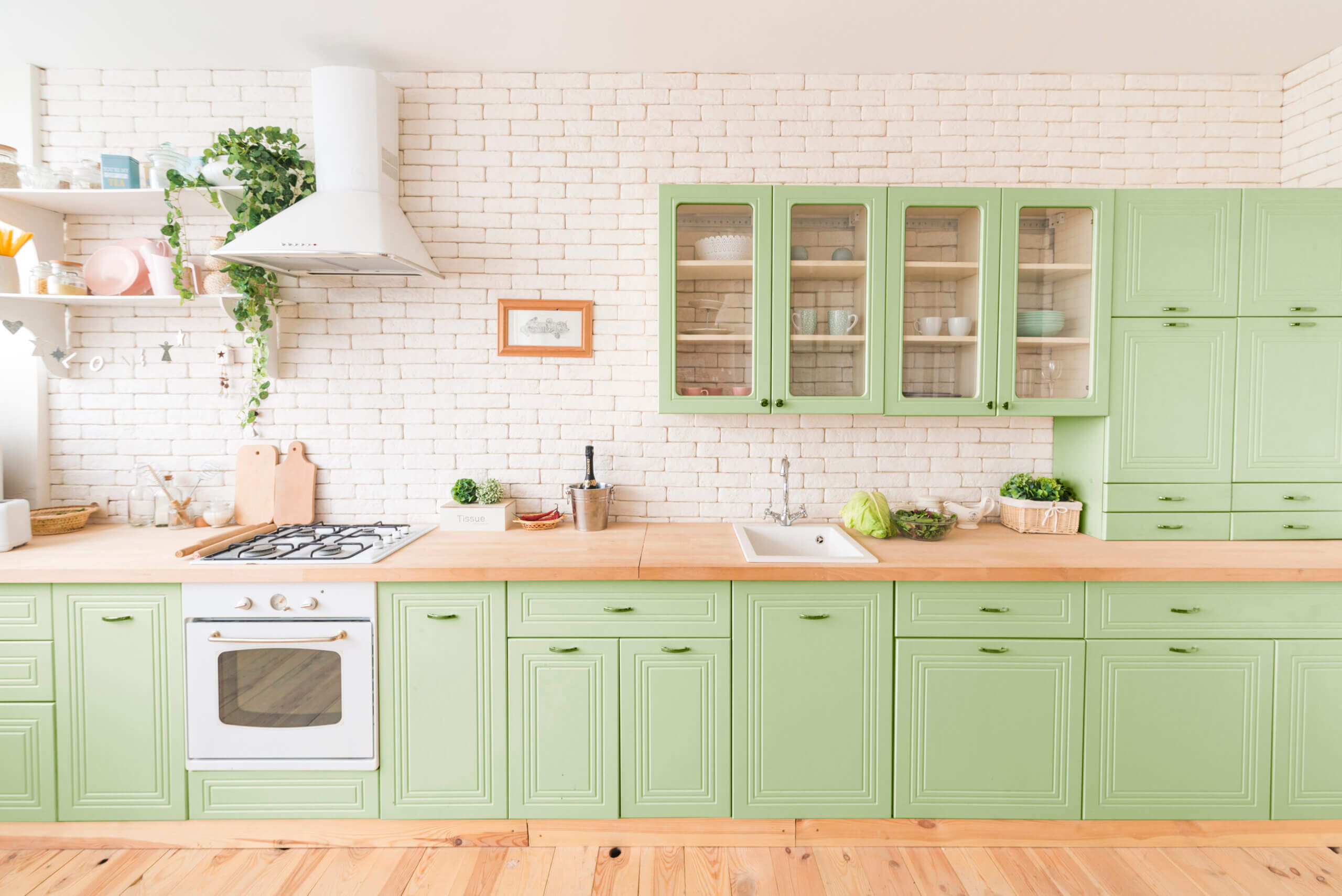 Bright kitchen with green cabinets and a touch of greenery